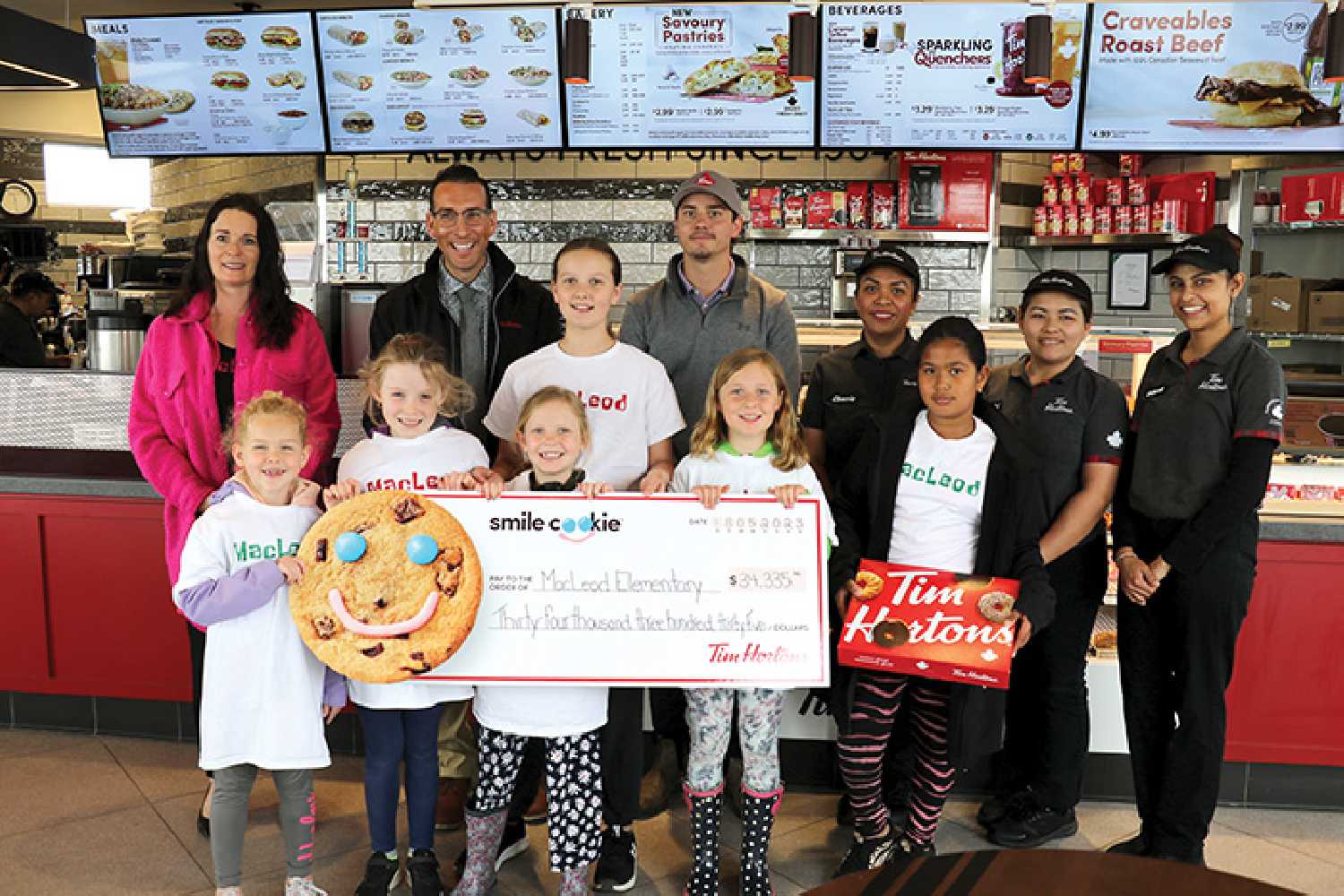 Principal Tammy Cole and students from MacLeod Penny Jeannot, Billee Kosier, Jessa Thorn, Hadley Miller, Anika Thorn and Casey  Caliwag thanked Moosomin Tim Hortons for their donation of $34,335 from Smile Cookie Week, which will go towards supporting the school’s playground project. <b>From left are,</b> Tammy Cole, Westman Tim Horton’s Owner Greg Crisanti, Tanner Bell district manager, Cherrie Caliwag store manager at Moosomin Tim Hortons, Nikki Romero and Jaspreet Kaur of Moosomin Tim Hortons.